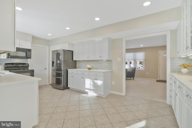 kitchen with tasteful backsplash, white cabinetry, black appliances, and light carpet