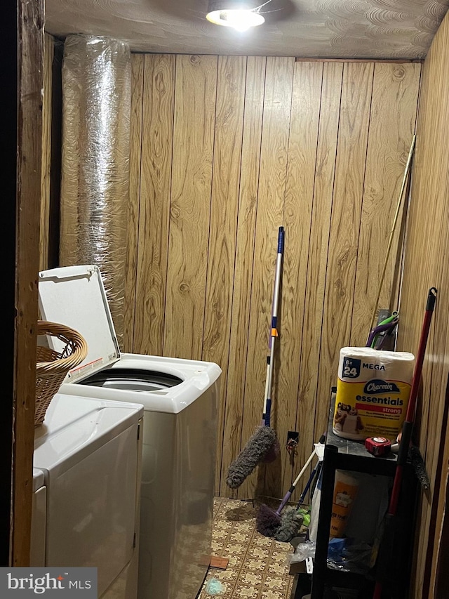 laundry room with separate washer and dryer and wood walls