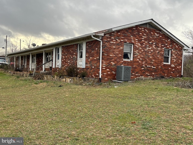 view of front of home featuring central AC unit, covered porch, and a front yard