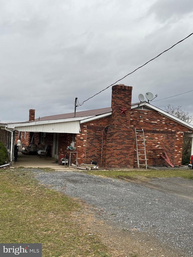560 Frosty Hollow Rd, Fisher, WV 26818 - view of side of home featuring a chimney, gravel driveway, and brick siding