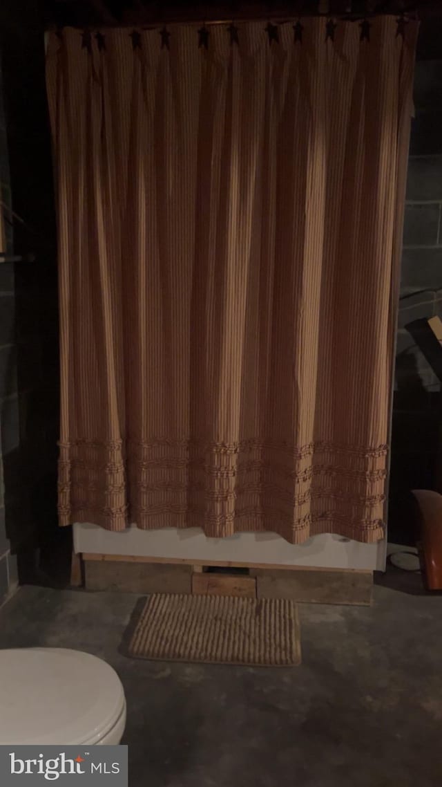 bathroom featuring walk in shower, concrete flooring, and toilet