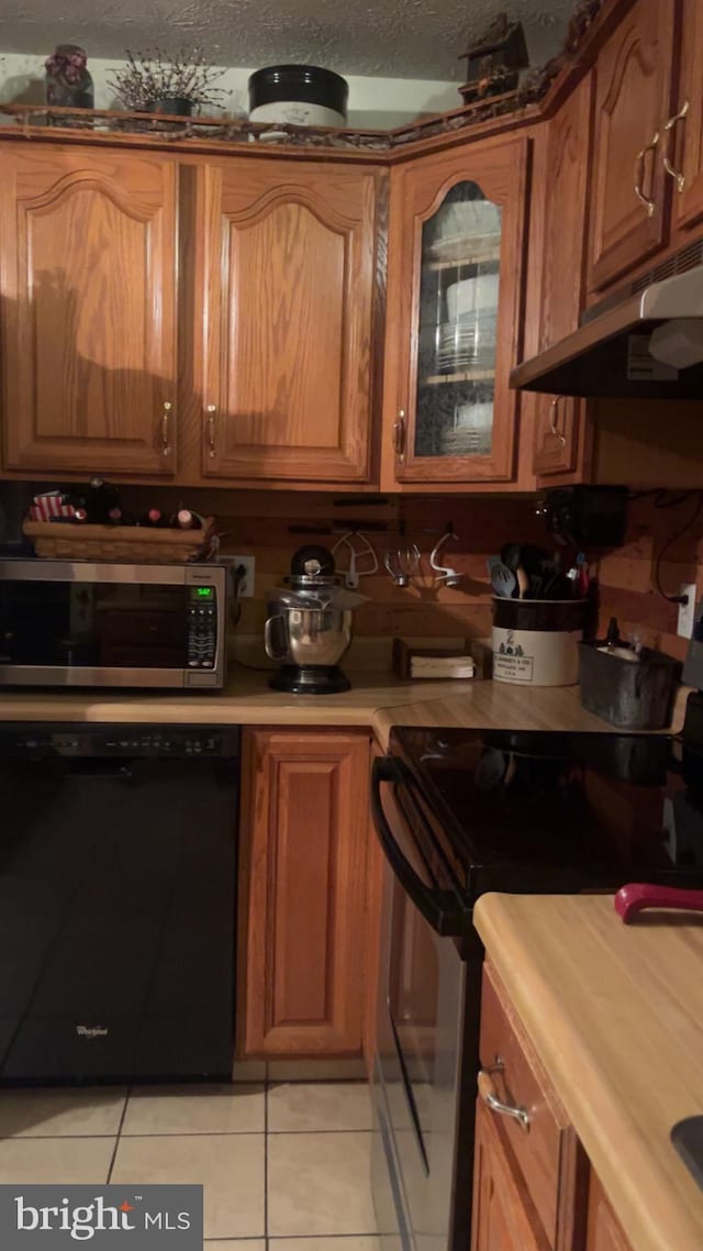 kitchen with light tile patterned floors, black appliances, and a textured ceiling