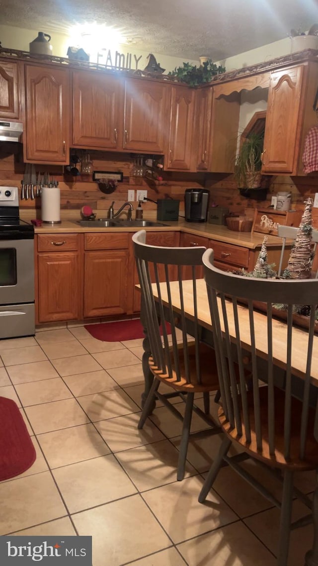 kitchen with light tile patterned floors, stainless steel electric stove, and sink