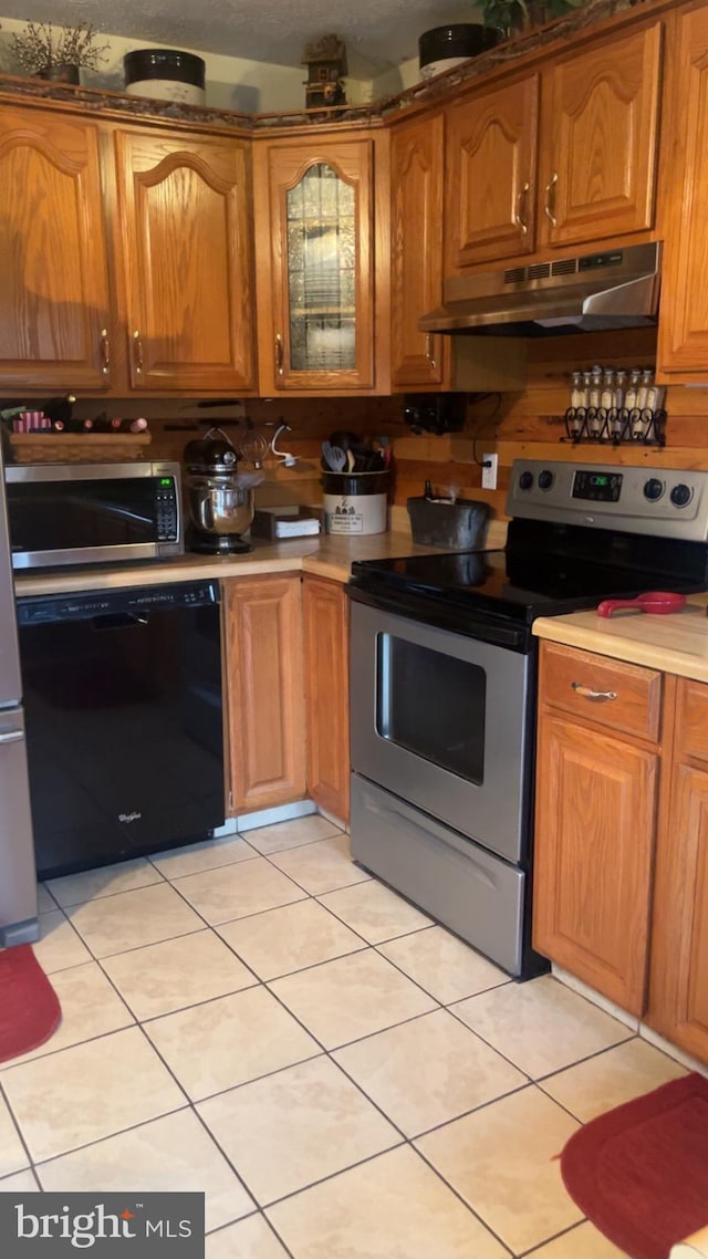 560 Frosty Hollow Rd, Fisher, WV 26818 - kitchen featuring under cabinet range hood, stainless steel appliances, light countertops, brown cabinets, and light tile patterned floors