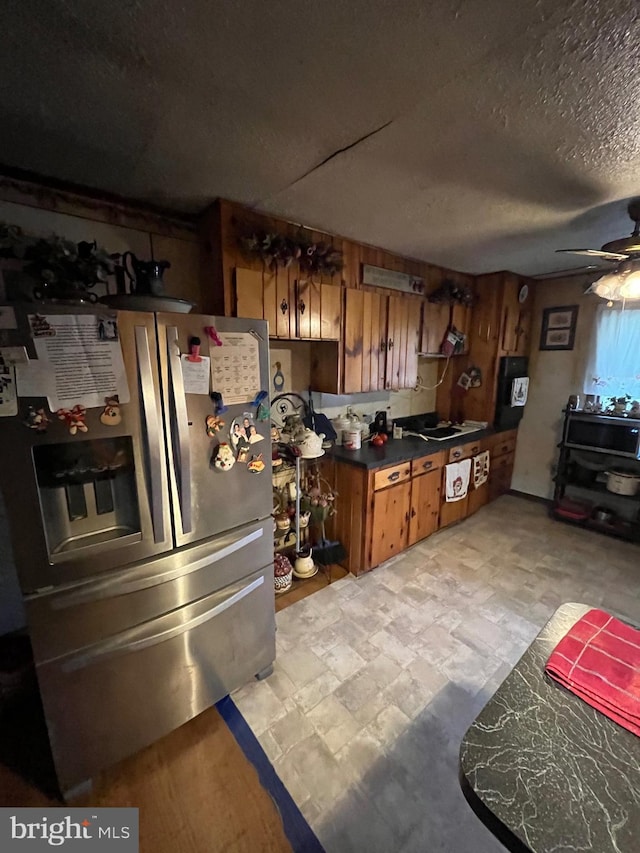 560 Frosty Hollow Rd, Fisher, WV 26818 - kitchen with stainless steel fridge with ice dispenser, brown cabinetry, dark countertops, ceiling fan, and a textured ceiling