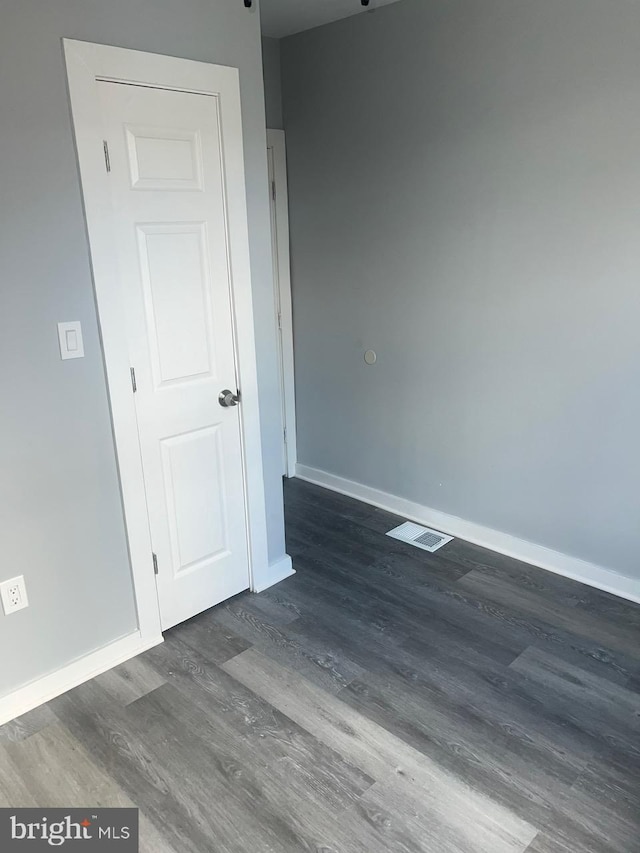 unfurnished room with dark wood-type flooring