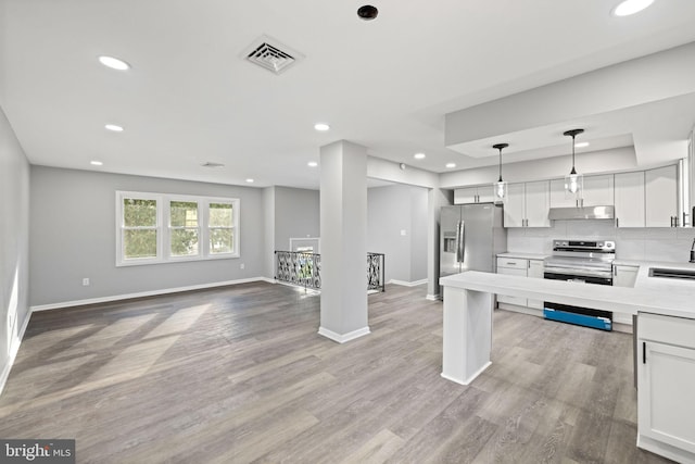 kitchen with appliances with stainless steel finishes, light wood-type flooring, sink, pendant lighting, and white cabinets