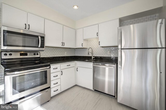 kitchen with white cabinets, appliances with stainless steel finishes, tasteful backsplash, and sink