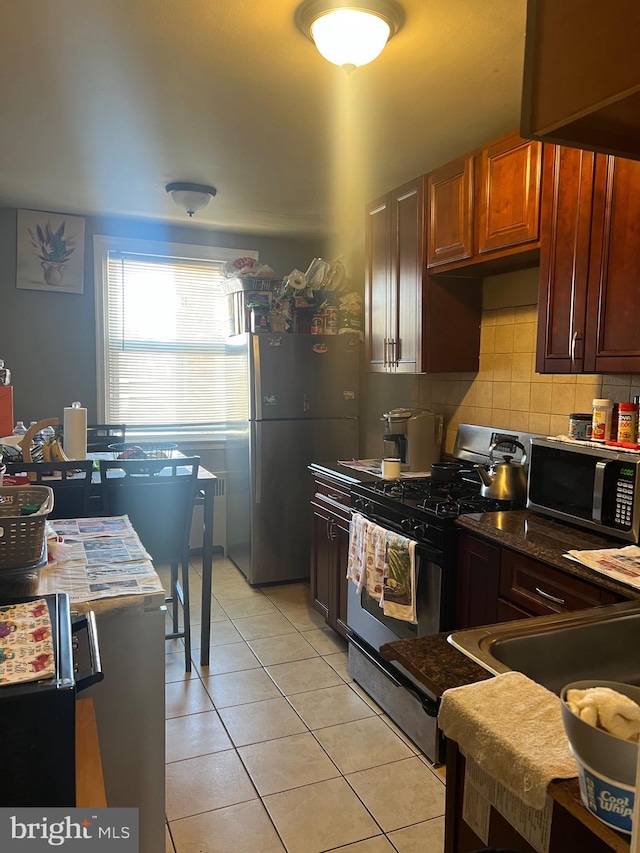 kitchen featuring decorative backsplash, appliances with stainless steel finishes, and light tile patterned floors