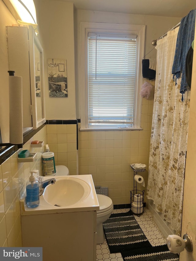 bathroom featuring a shower with curtain, tile patterned flooring, toilet, vanity, and tile walls