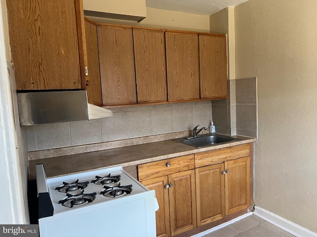 kitchen featuring backsplash, ventilation hood, white range with gas cooktop, sink, and light tile patterned floors