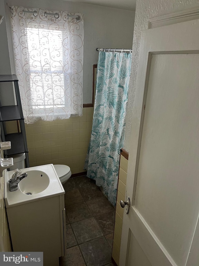 bathroom featuring vanity, tile patterned flooring, toilet, tile walls, and curtained shower