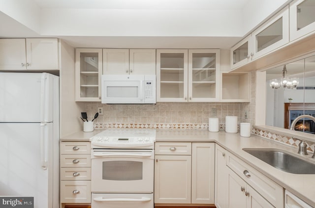 kitchen featuring sink, tasteful backsplash, a notable chandelier, decorative light fixtures, and white appliances