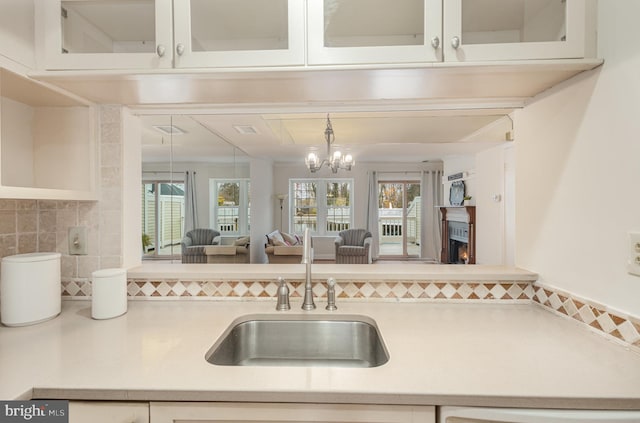 kitchen featuring backsplash, an inviting chandelier, a wealth of natural light, and sink