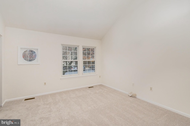 empty room featuring light colored carpet and vaulted ceiling