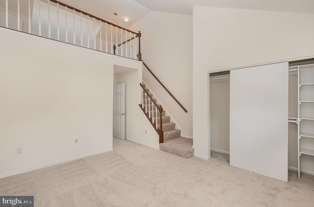 unfurnished living room featuring light colored carpet and high vaulted ceiling