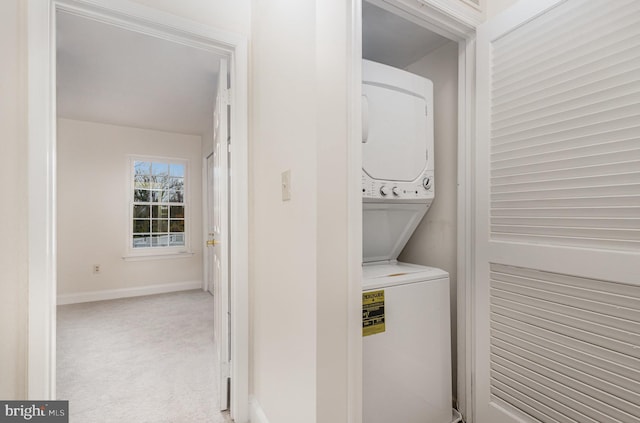 clothes washing area featuring stacked washer / dryer and light carpet