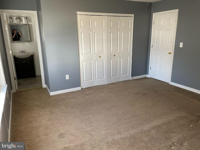 unfurnished bedroom with carpet flooring, sink, connected bathroom, and a closet