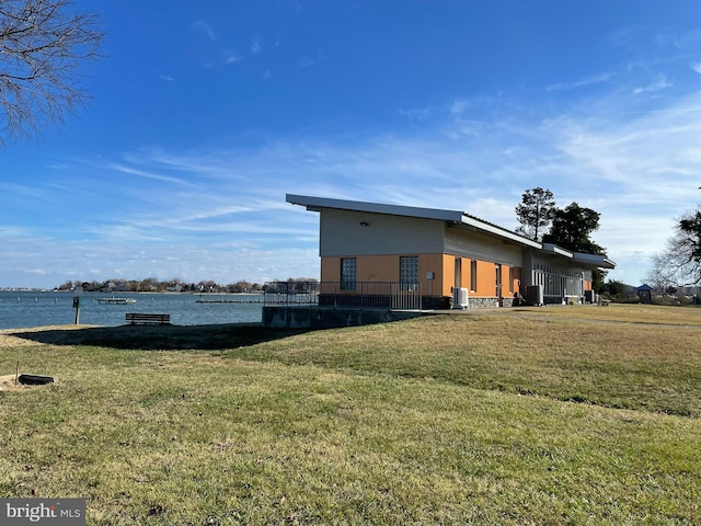 exterior space featuring a lawn, a water view, and central AC unit