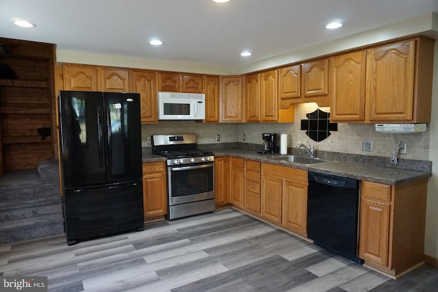 kitchen with backsplash, light hardwood / wood-style flooring, black appliances, and sink