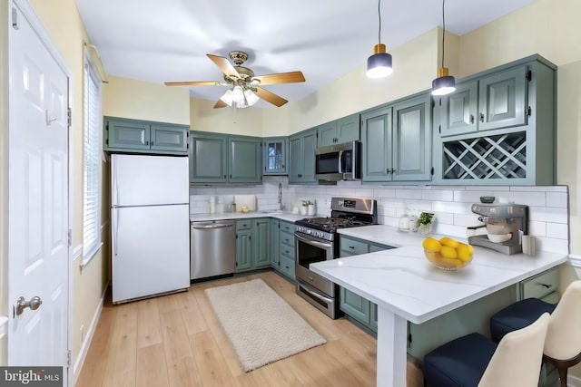 kitchen featuring kitchen peninsula, a kitchen breakfast bar, tasteful backsplash, stainless steel appliances, and pendant lighting