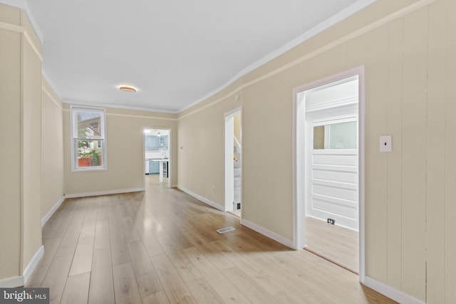 spare room featuring crown molding and light wood-type flooring