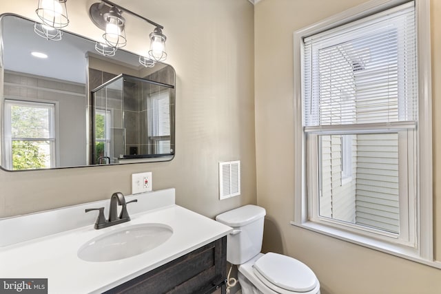 bathroom with vanity, toilet, and a shower with door