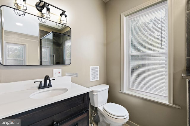 bathroom featuring a wealth of natural light, toilet, vanity, and walk in shower