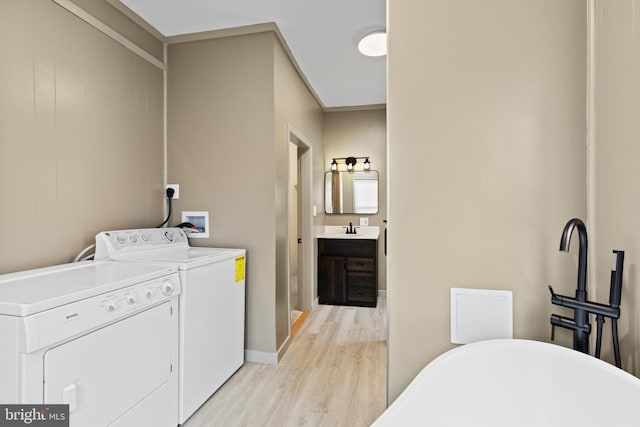 washroom featuring washer and clothes dryer, light hardwood / wood-style floors, and sink