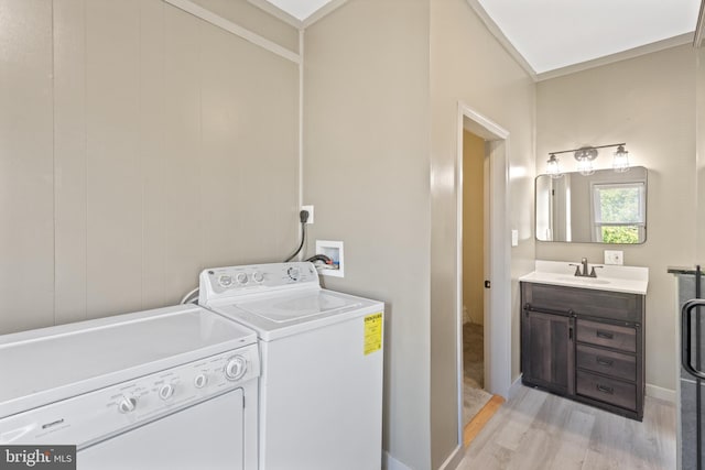 laundry room featuring washer and clothes dryer, light hardwood / wood-style floors, and sink