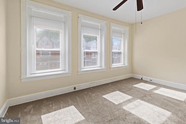 carpeted spare room featuring ceiling fan