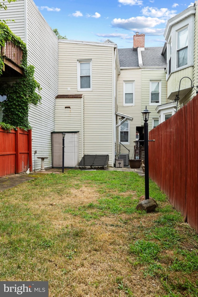 back of house featuring central AC and a yard