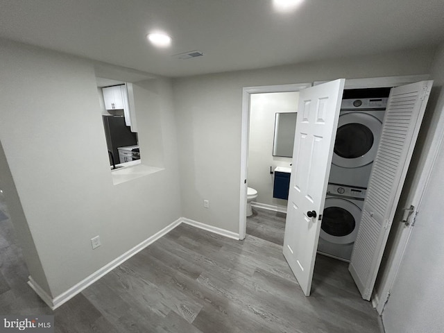 laundry area with wood-type flooring and stacked washer and clothes dryer