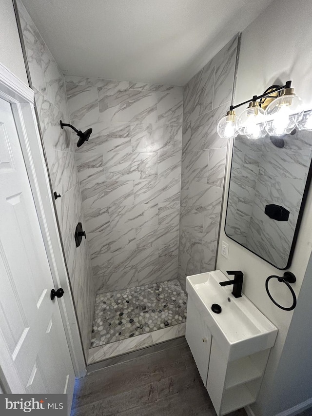 bathroom featuring hardwood / wood-style floors, vanity, and a tile shower