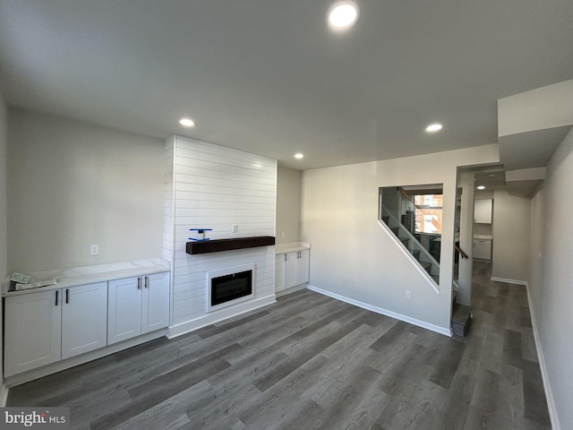 unfurnished living room with dark hardwood / wood-style floors and a large fireplace