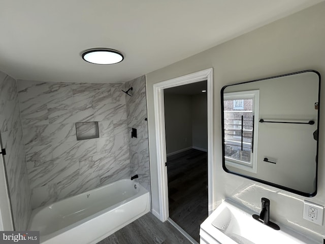 bathroom with hardwood / wood-style flooring, tiled shower / bath combo, sink, and vaulted ceiling