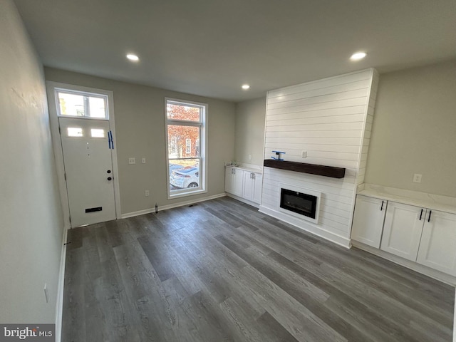 unfurnished living room featuring a fireplace and dark wood-type flooring