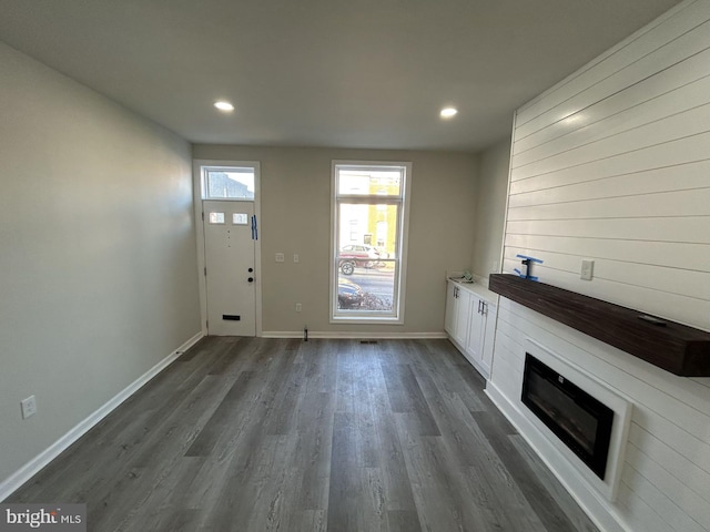 unfurnished living room featuring a large fireplace and dark wood-type flooring