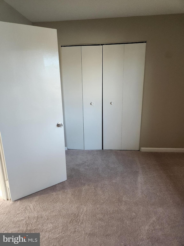 unfurnished bedroom featuring a closet and light colored carpet