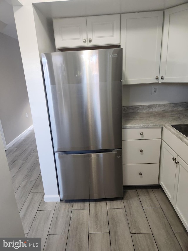 kitchen featuring white cabinets, stainless steel fridge, and light hardwood / wood-style flooring