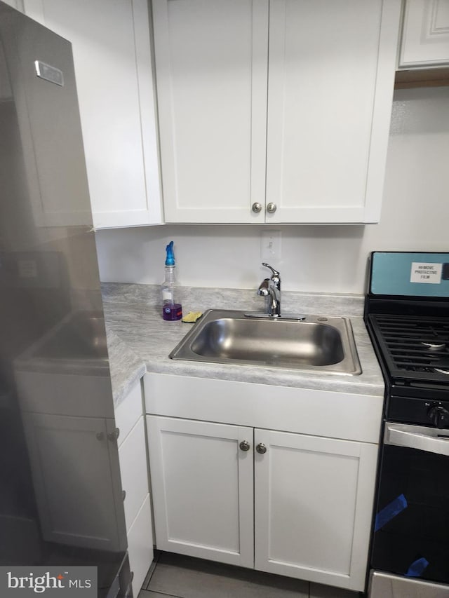 kitchen featuring sink, white cabinets, and stainless steel range oven