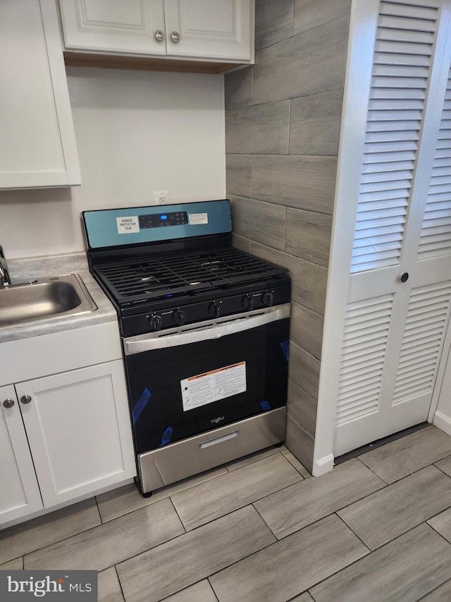 kitchen featuring white cabinetry, sink, and stainless steel gas range