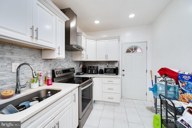 kitchen with white cabinetry, electric range, sink, wall chimney range hood, and decorative backsplash