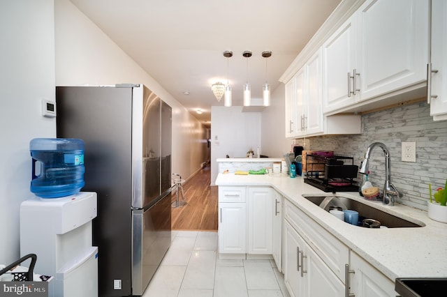 kitchen featuring sink, stainless steel appliances, pendant lighting, light hardwood / wood-style floors, and white cabinets