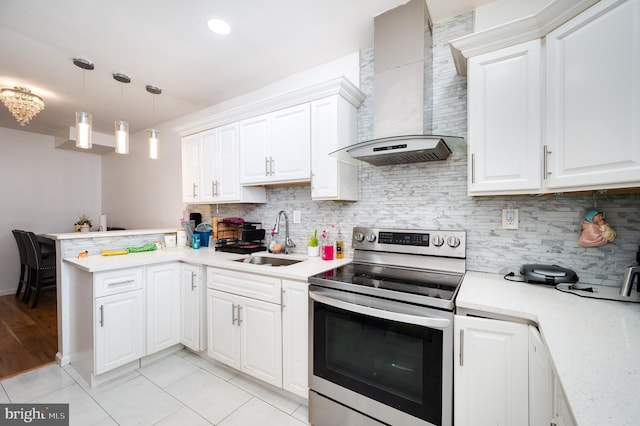 kitchen with kitchen peninsula, electric range, white cabinetry, and wall chimney range hood