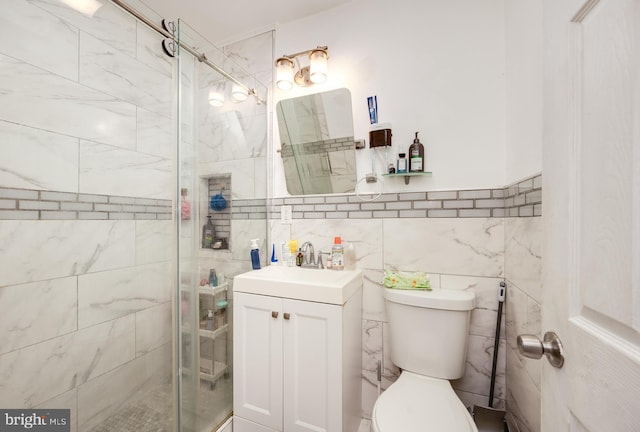 bathroom with vanity, a shower with door, toilet, and tile walls