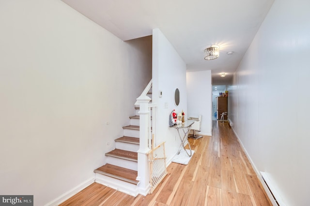 stairway featuring wood-type flooring and a baseboard heating unit