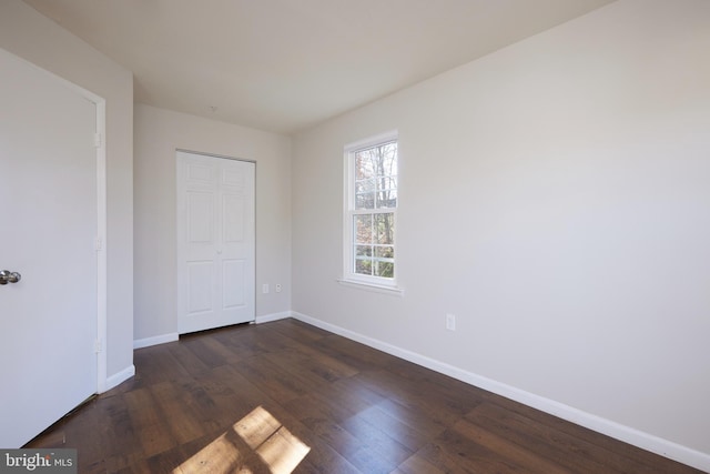 unfurnished bedroom featuring dark wood-type flooring and a closet