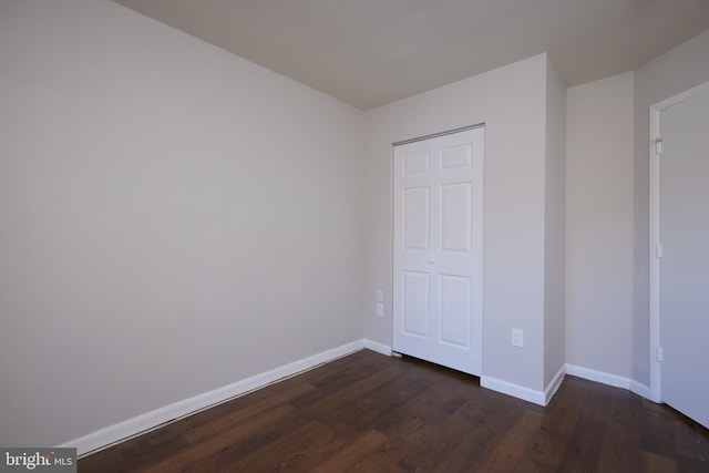 unfurnished bedroom featuring a closet and dark wood-type flooring