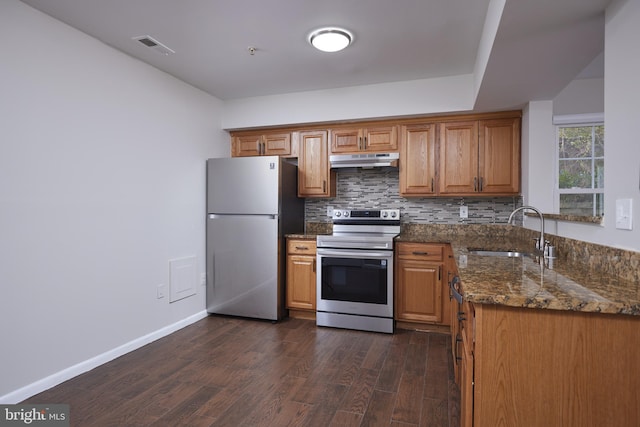 kitchen featuring backsplash, sink, dark hardwood / wood-style floors, dark stone countertops, and stainless steel appliances